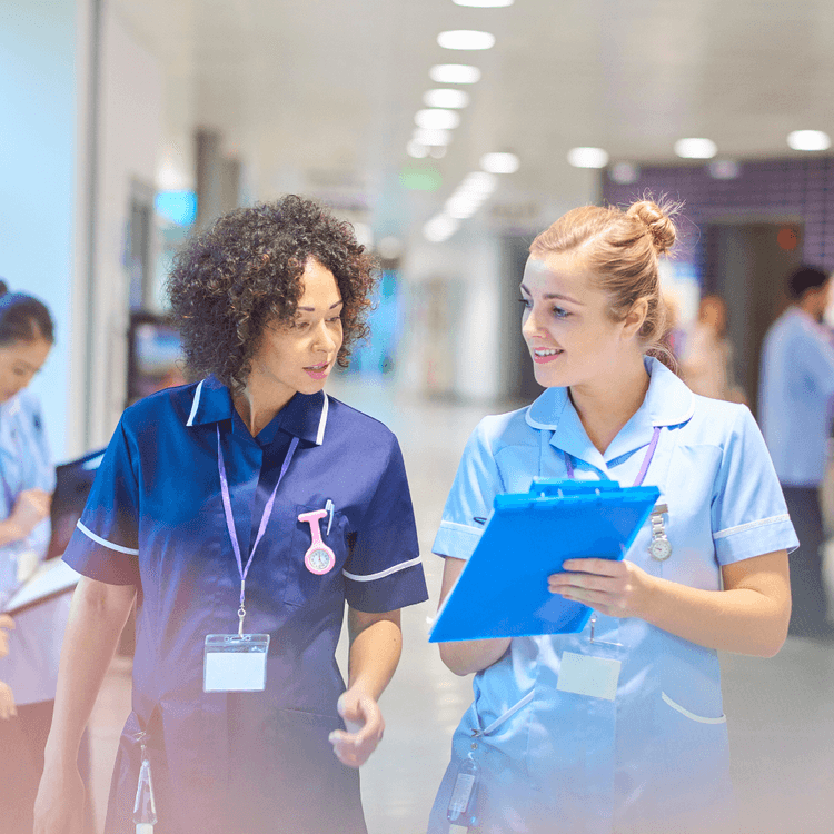 Zwei Pflegerinnen, die im Gehen miteinander sprechen