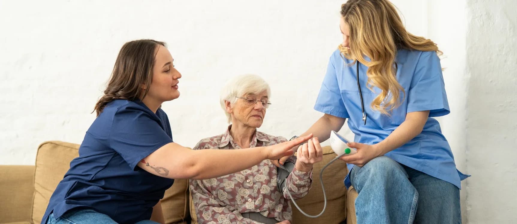 Altenpflegerin zeigt Kollegin, wie sie richtig Blutdruck misst