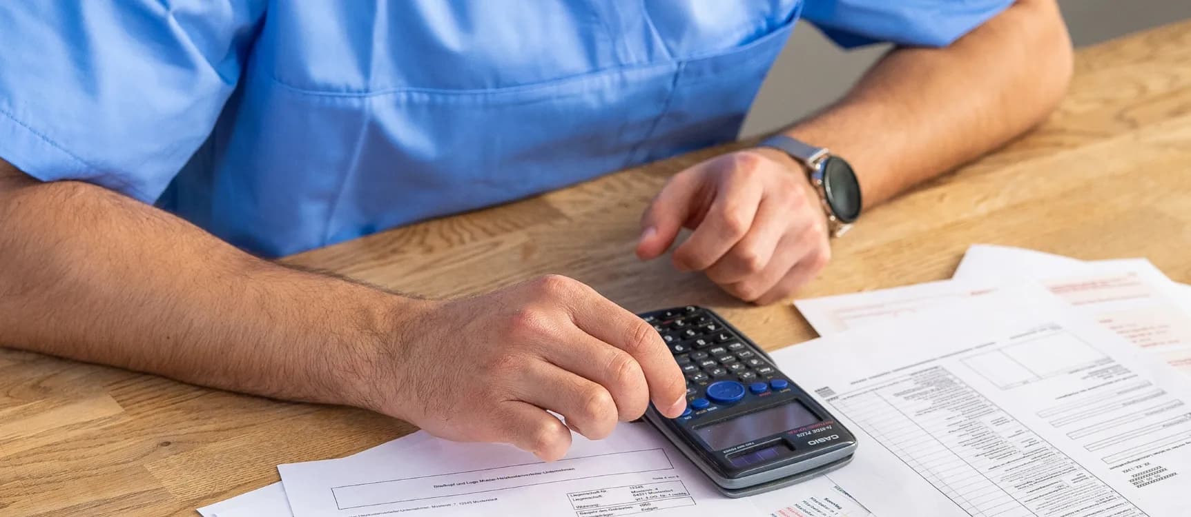 Mann berechnet Gehalt auf dem Taschenrechner in der generalistischen Pflegeausbildung