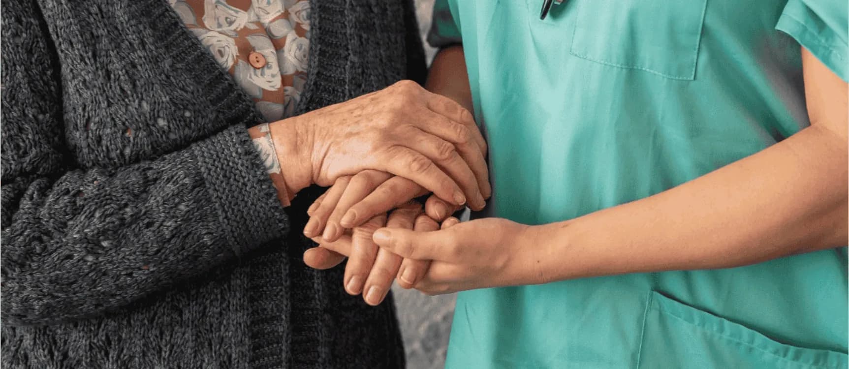 Pflegeassistentin hält Hand von Patientin