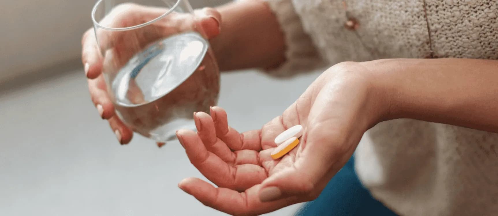 Frau hält ein Glas Wasser und Vitam-Tabletten in der Hand