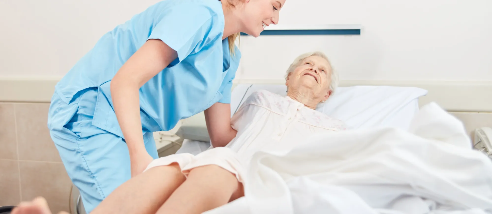 Pflegefachkraft hilt älterer Patientin beim Umlegen