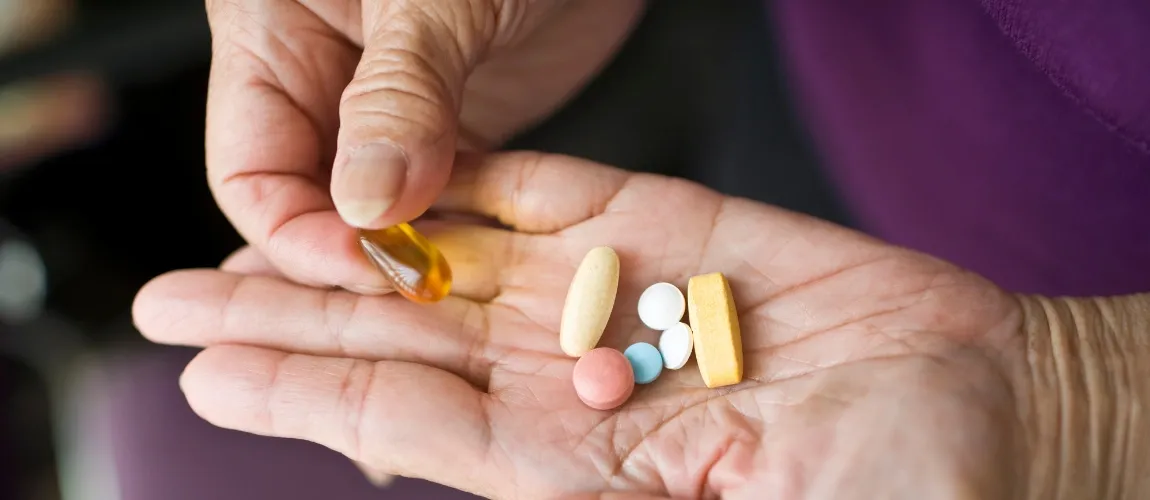 Eine ältere Frau hat verschiedene Medikamente in der Hand. 