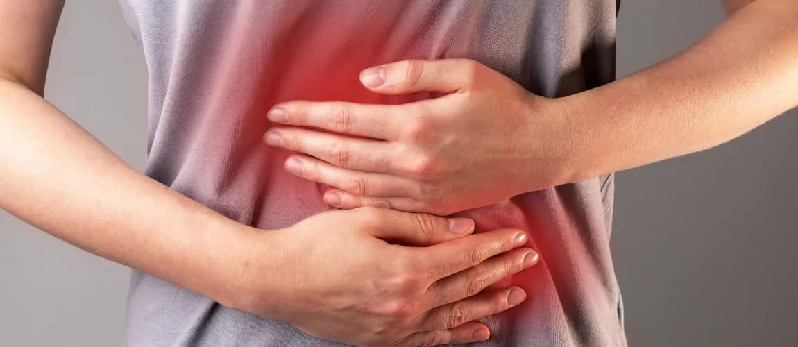 Es ist eine Frau mit Schmerzen im Bauchbereich zu sehen. 