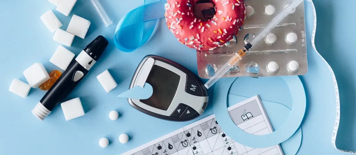 Nahaufnahme unterschiedlicher Dinge auf einem Tisch: Darunter Tabletten, Spritze und Zuckerwürfel.