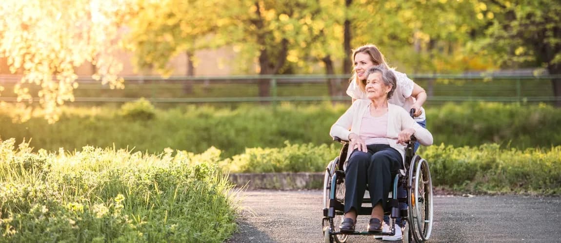 Pflegende Angehörige im Urlaub mit pflegebedürftiger Person im Rollstuhl 
