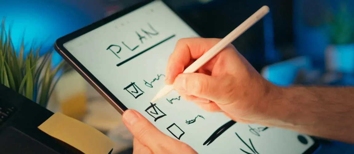 Eine Person schreibt mit einem Stift auf einem Tablet.