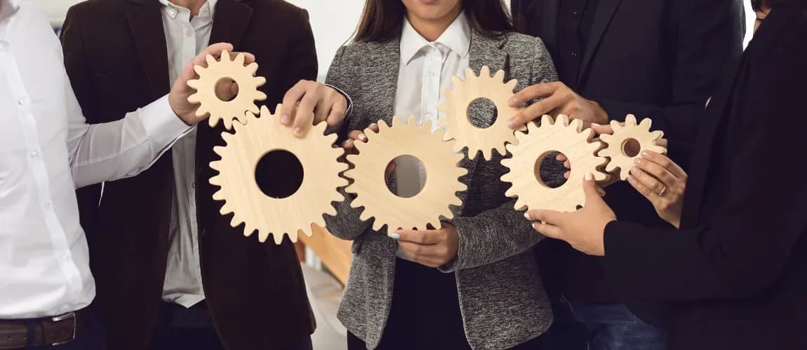 Eine Gruppe von Menschen hält Zahnräder aus Holz in der Hand. 