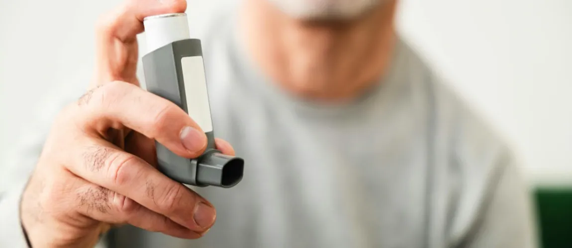 Ein Mann hält ein Asthma-Spray in die Kamera