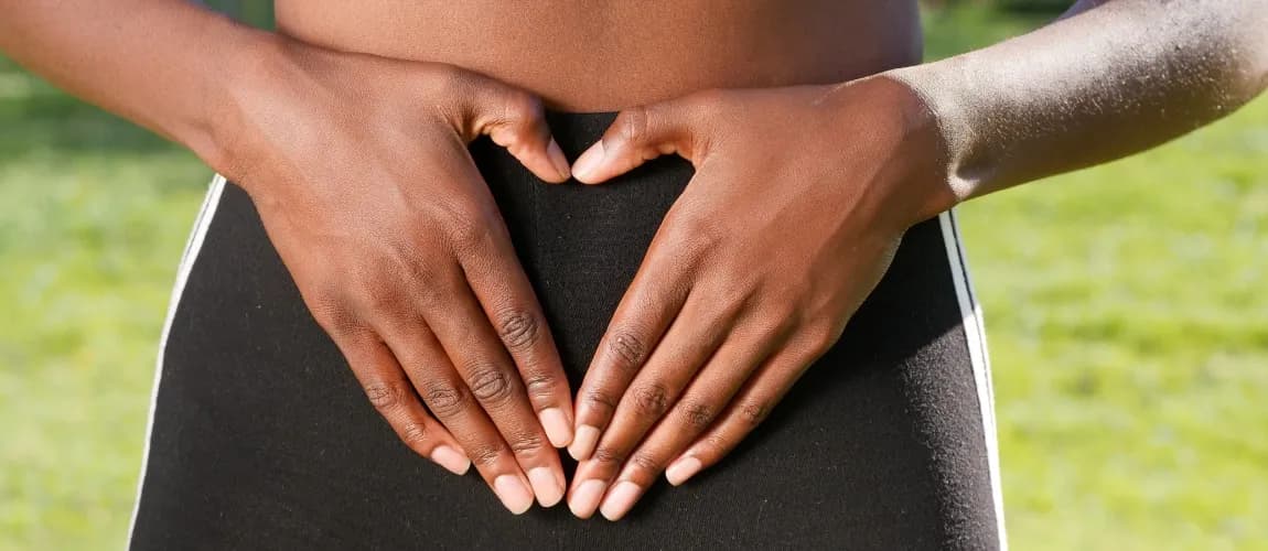 Eine Frau formt mit beiden Händen ein Herz vor dem Bauch.