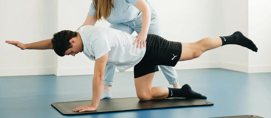 Eine Physiotherapeutin hilft einem Patienten, das Gleichgewicht bei einer Übung zu halten. 