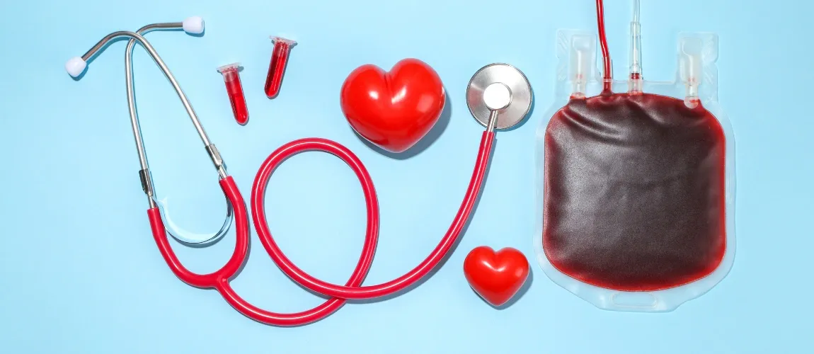 Ein Stethoskop, ein Blutbeutel und Herzformen sind vor einem blauen Hintergrund angeordnet.