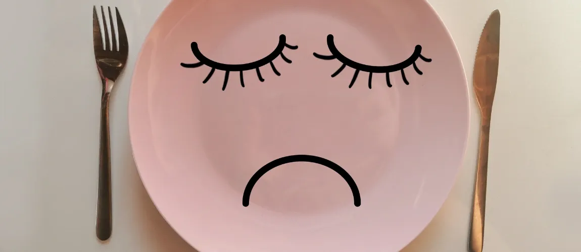 Ein rosa Teller mit einem "Gesicht" abgebildet, daneben liegt Besteck. 