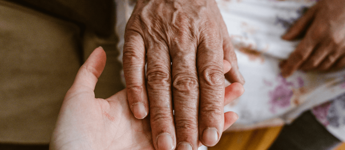 Eine junge Hand hält eine ältere Hand.