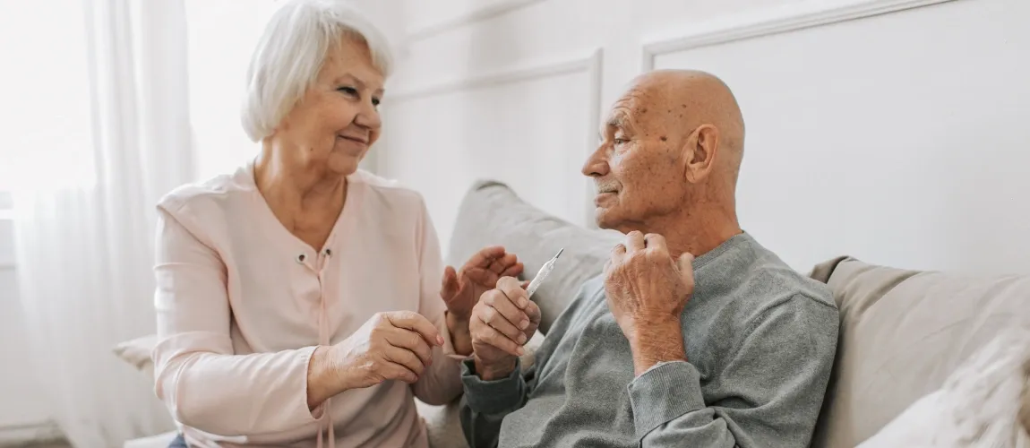 Ein älteres Paar sitzt auf einem Sofa.