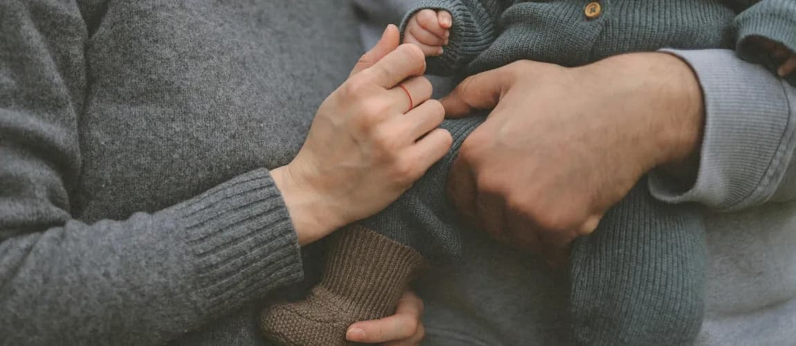 Ein Elternpaar hält ein Baby auf dem Arm.