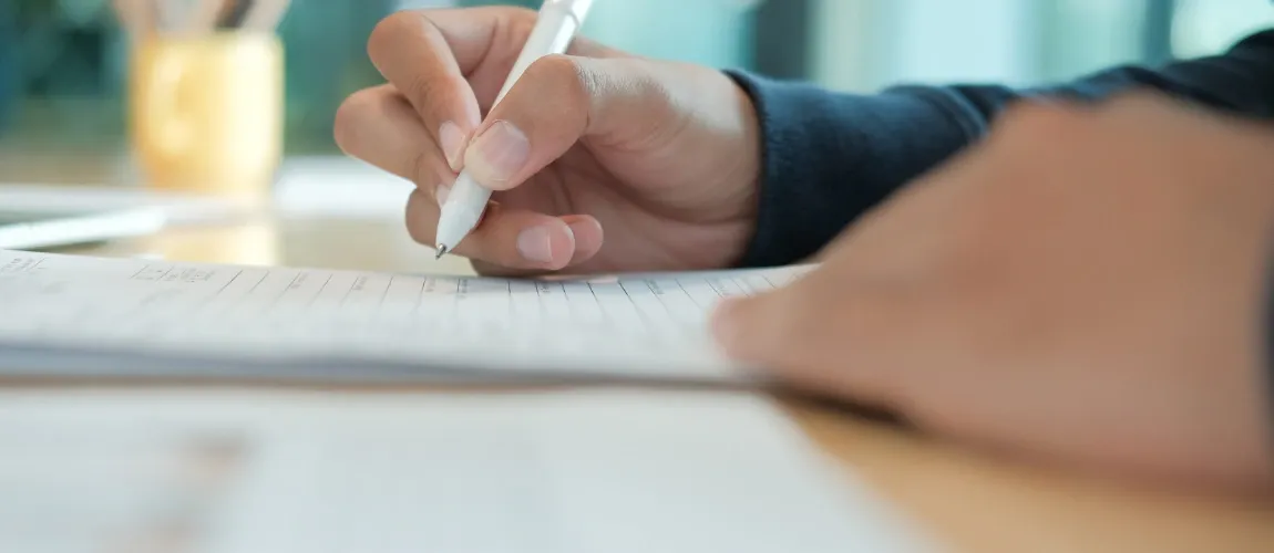Nahaufnahme einer Hand die einen Stift greift und etwas schreibt.