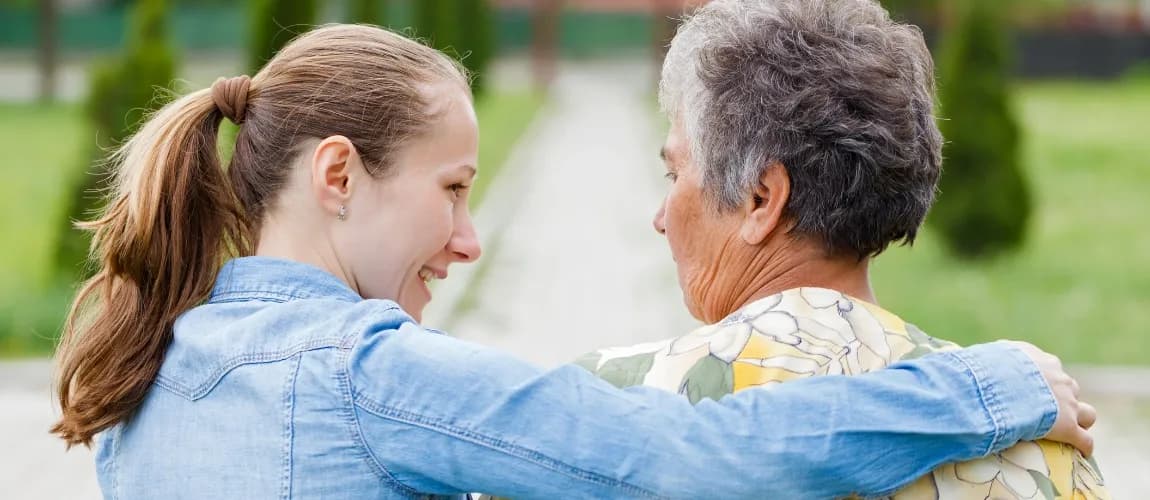 Eine Pflegerin legt den Arm um eine Patientin.