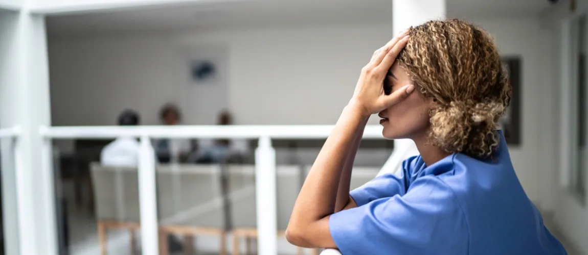 Ist Pflege ohne Schichtdienst möglich? Erschöpfte Frau greift sich an den Kopf
