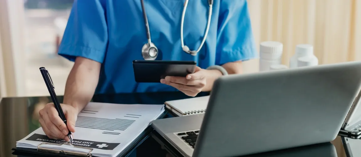 Pflegekraft arbeitet an einem Laptop.