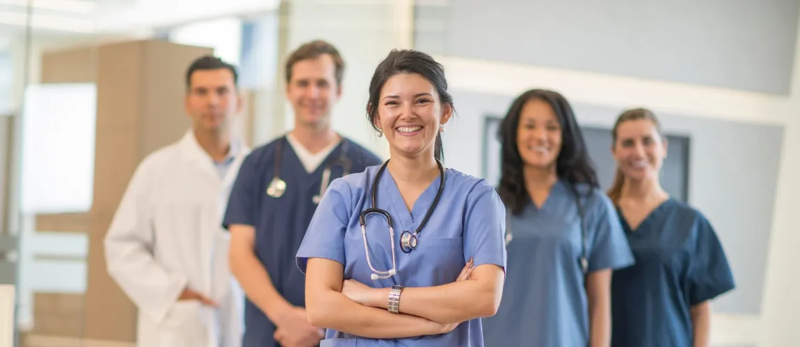 Pflegekraft mit Leitungstätigkeit steht gemeinsam mit ihren Kollegen